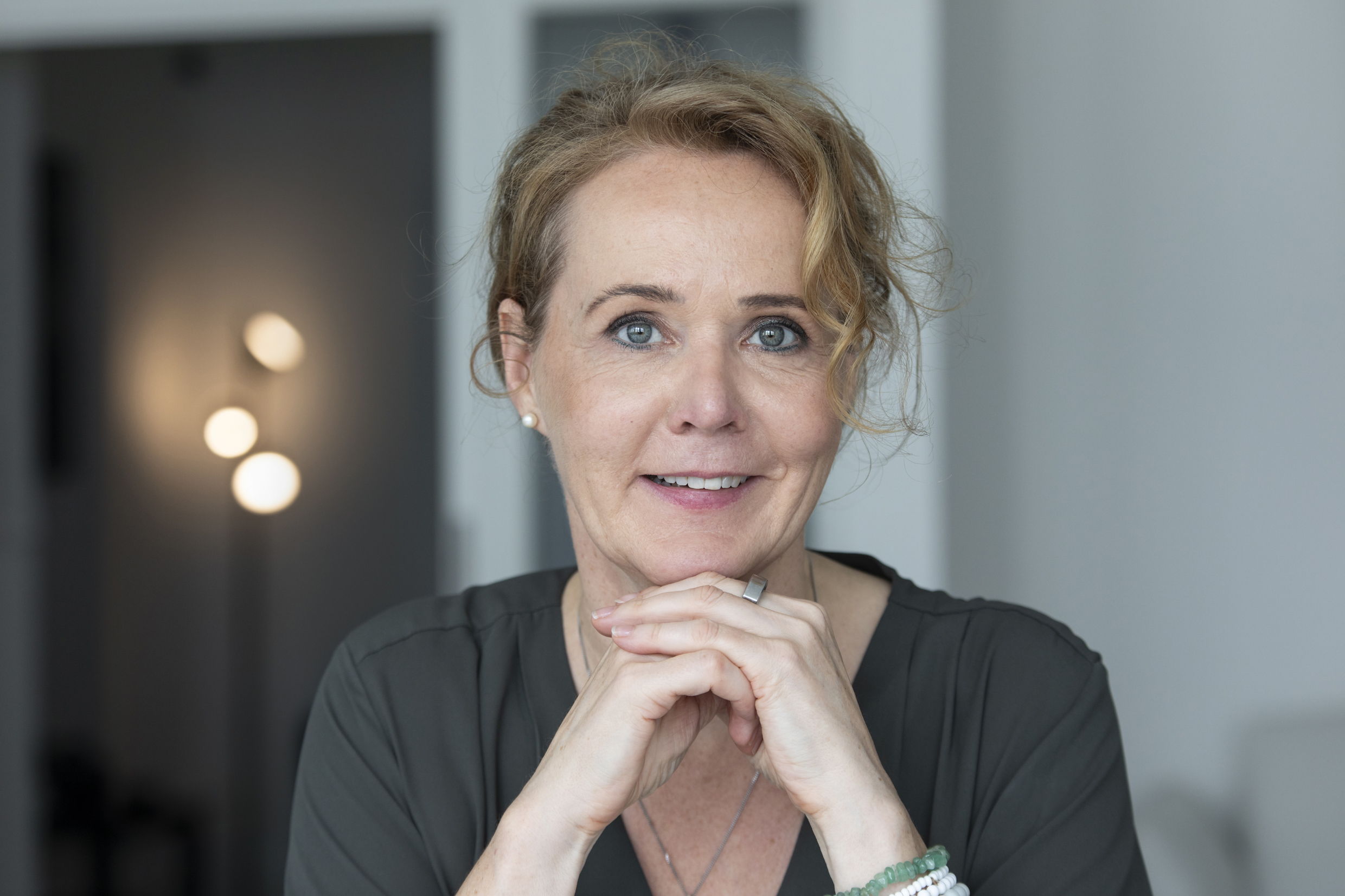 Ein blonde Frau schaut lächelnd in die Kamera.